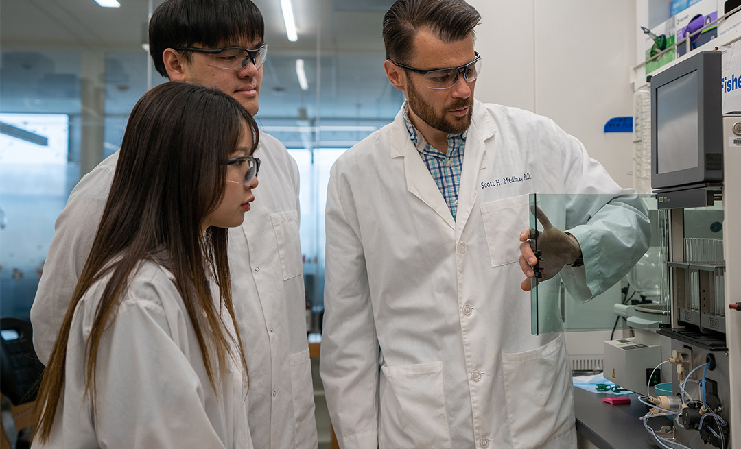 researchers in lab coats standing in a lab